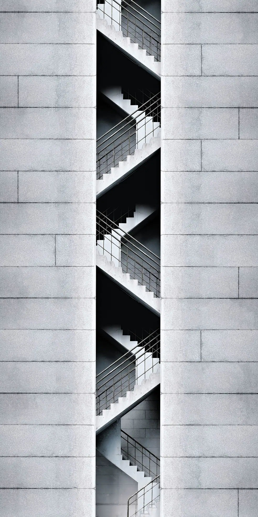 A stair core seen through a slot in a grey tiled facade