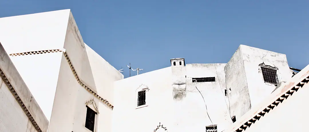 Whitewashed walls and parapets of a Moroccan medina against a clear sky