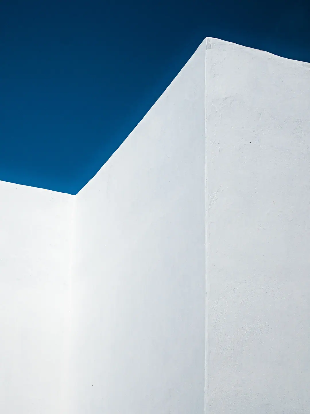 The corner of a whitewashed wall against a deep blue sky