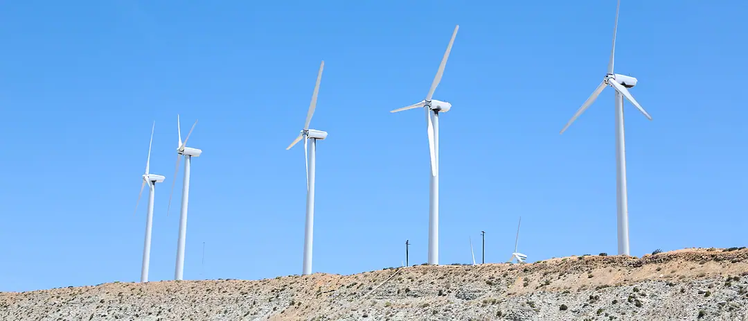 Wind turbines along a rocky ridge under a clear sky